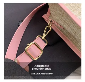 Close-up of adjustable pink leather shoulder strap with gold buckle on a straw bag