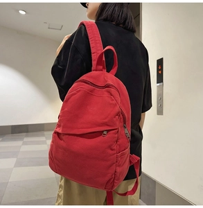 Detailed side view of a large red canvas backpack worn by a model in a modern interior