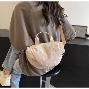 Close-up of beige pleated fabric texture on a stylish urban crossbody shoulder bag