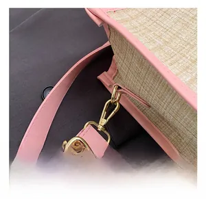 Detailed close-up of premium gold metal hooks and pink leather straps on straw tote bag
