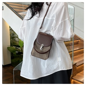 Detail of a vintage-style PU leather crossbody bag with silver clasp and textured material