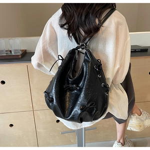 Detail view of black faux leather backpack with decorative 3D bows and large capacity