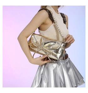 Detail of metallic gold PU shoulder bag with oversized bow and chain strap design