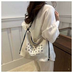 Close-up of a white canvas tote bag featuring black lettering and fine shoulder straps