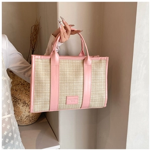 Close-up of beige woven texture and pink leather handle with logo on a summer tote bag