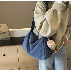 Detail of blue nylon crossbody bag with curved design and cute plush coffee cup charm