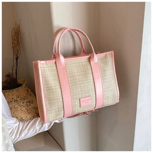 Detail of summer straw tote bag with pink leather handles and brand label on front