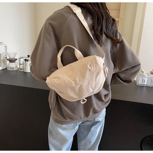 Detail of a beige nylon crossbody bag with adjustable wide strap and soft texture finish
