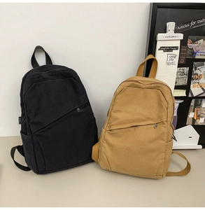 Detail view of durable canvas backpacks in black and mustard yellow with side pockets