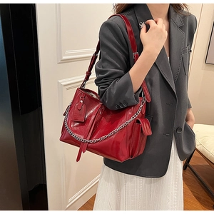 Detail of red faux leather shoulder bag with silver chain strap and side pocket detail
