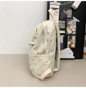 Side view of cream white canvas backpack showing side pocket and durable padded shoulder straps
