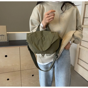 Detail of army green nylon crossbody bag with geometric folding flap and drawstring lock