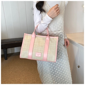 Close-up of pink leather trim and beige woven texture on the fashion straw tote bag