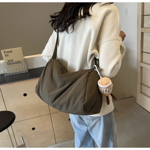 Deep olive crossbody bag with coffee cup plush charm showing a casual oversized slouchy style