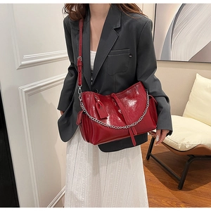 Detail of dark red patent leather crossbody bag with silver chain and fringe tassel