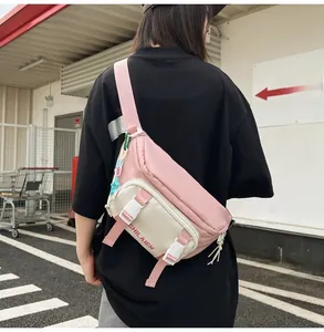 Detail of trendy nylon waist bag in pink and beige with wide strap and star charm