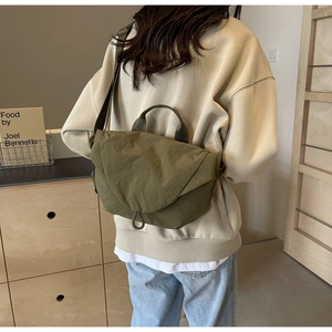 Olive green nylon messenger bag with wrinkled texture and adjustable strap in lifestyle setting