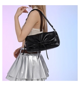 Detailed view of a black pleated PU leather handbag featuring a stylish decorative bow