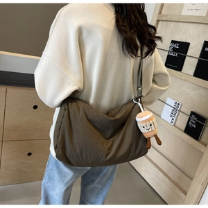 Detail of a large brown crossbody nylon bag with a cute coffee cup plush charm