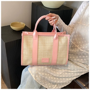 Detail of summer straw woven crossbody bag with pink leather trim and top handles