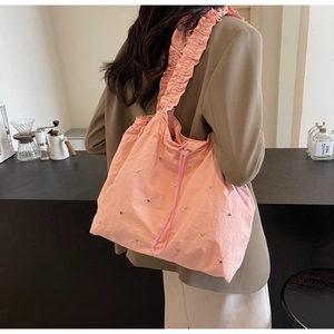Detailed view of pink drawstring tote with ruched straps and silver stud accents