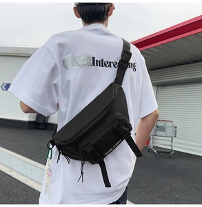 Detailed view of black nylon waist bag with tactical buckle worn on model back