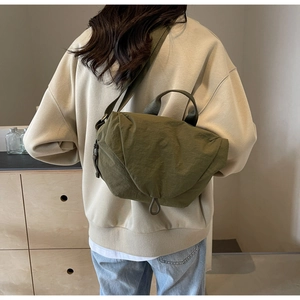 Army green nylon crossbody bag styled by model in a minimalist lifestyle setting