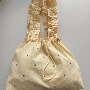 Minimalist beige nylon handbag with drawstring and ruffle strap featuring silver rhinestones