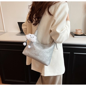 Detail view of silver PU leather crossbody bag with cloud plush charm and branding