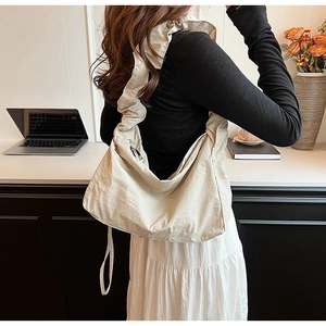 Detail of cream nylon crossbody bag featuring ruffled strap and pleated fabric texture