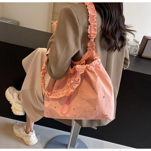 Detail of pink ruffled tote bag with silver studs and drawstring closure on shoulder