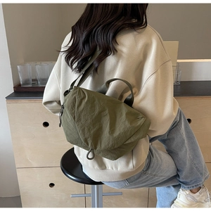 Detail of army green nylon crossbody bag with micro-wrinkle texture and top handle grip