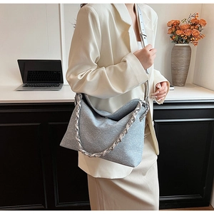 Detail of glittery light blue tote bag featuring a chunky silver chain strap on a model