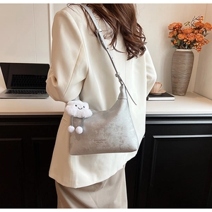 Silver PU leather hobo bag with a white plush cloud charm shown in a casual office setting