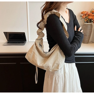 Detail of beige nylon crescent bag featuring ruched strap and silver zipper closure