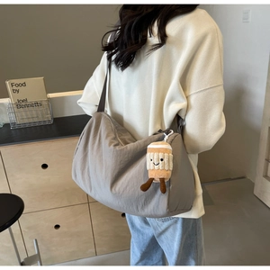 Close-up of a grey nylon crossbody bag with a cute coffee cup plush charm and large capacity