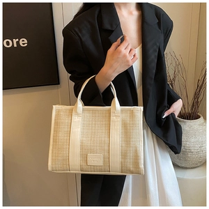 Detail of beige straw weave shoulder bag with white leather trim and square logo patch