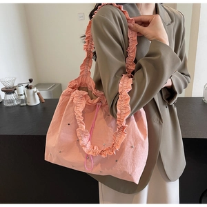 Detail of pink ruffled tote bag with silver studs and drawstring on shoulder strap