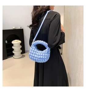 Detail of light blue quilted bubble bag texture and adjustable strap on black dress