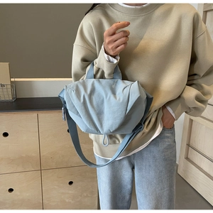 Close-up of stylish light blue-grey quilted crossbody bag with soft textured fabric material