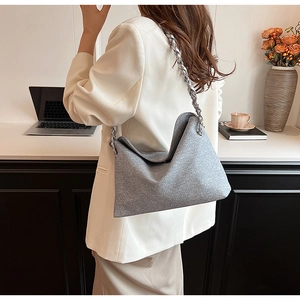 Grey shimmering hobo bag with a chunky silver metal chain strap worn by a female model