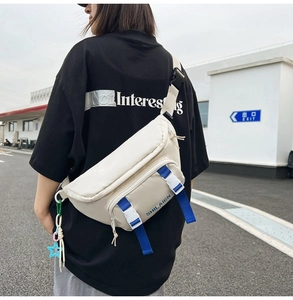 Outdoor shot of cream nylon fanny pack with blue strap and white buckle detail