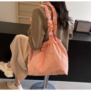 Detailed shot of pink fabric tote bag featuring ruffled strap and silver studded accents