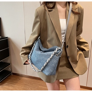 Close-up of blue denim texture tote bag with silver chain strap worn with a blazer