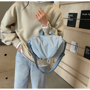 Detail of light blue pleated nylon crossbody bag showing adjustable strap and soft texture