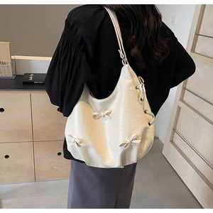 Détail du sac à bandoulière blanc crème en cuir froissé avec trois nœuds décoratifs 3D