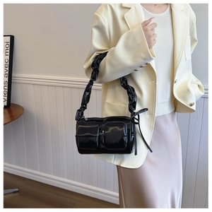 Detail of black glossy PU shoulder bag with pleated straps and front flap pockets