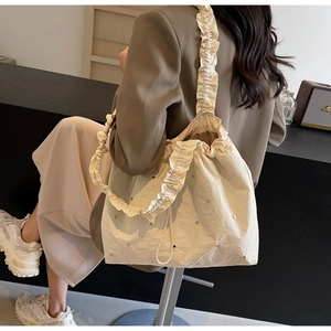 Detail of beige pleated tote bag with sparkling rhinestones and soft ruffled edge
