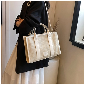 Detail view of woven straw tote bag with cream leather trim and shoulder strap for summer