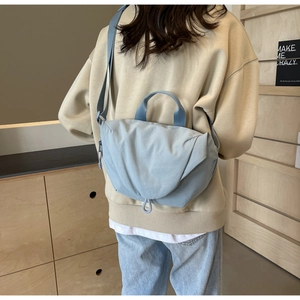 Back view of model wearing a light blue crossbody nylon bag with adjustable wide shoulder strap